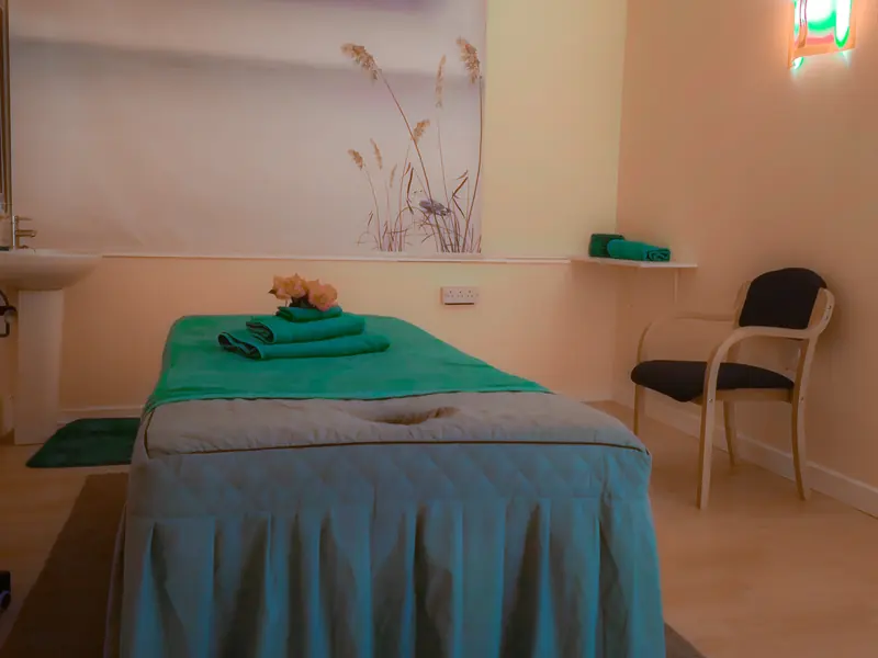 Treatment room one with a green-towelled massage table