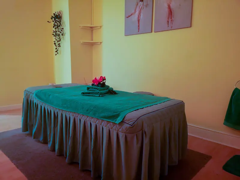 A treatment room with a massage table, fresh towels and flowers
