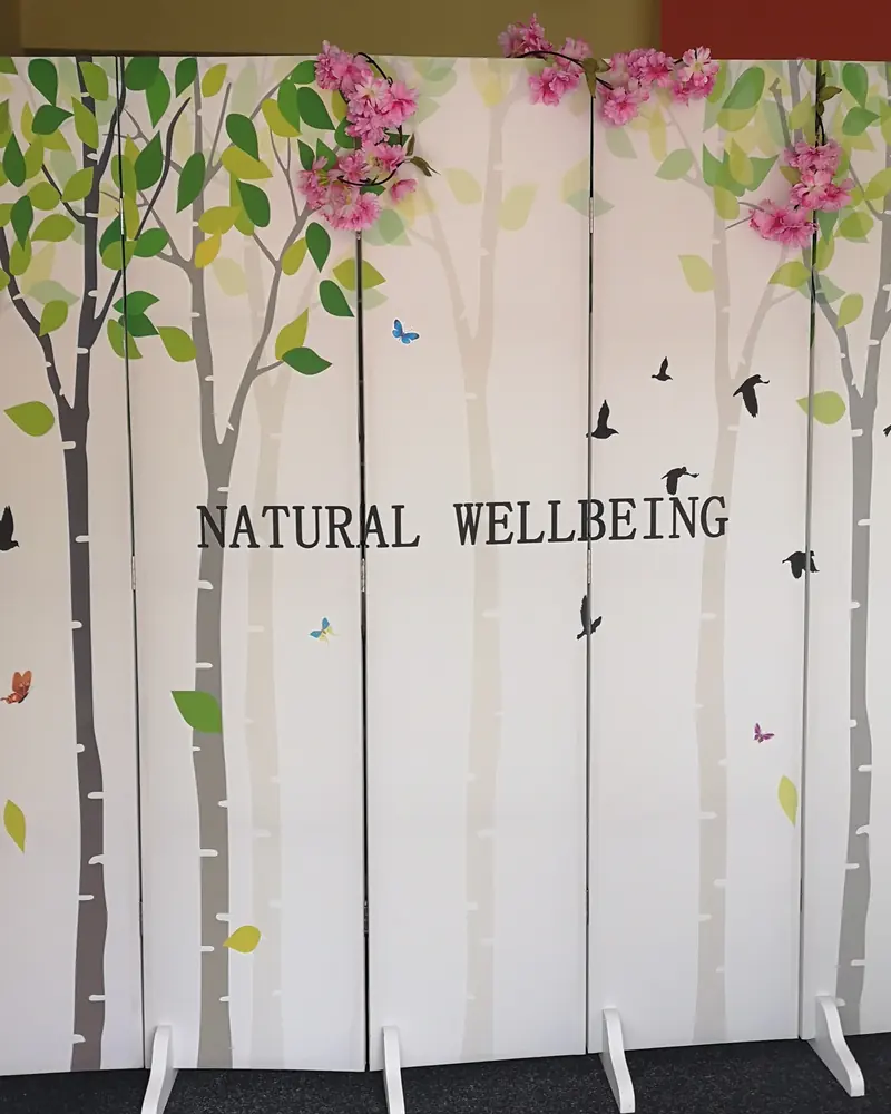 The Natural Wellbeing sign on a birch-tree screen decorated with cherry blossom in reception